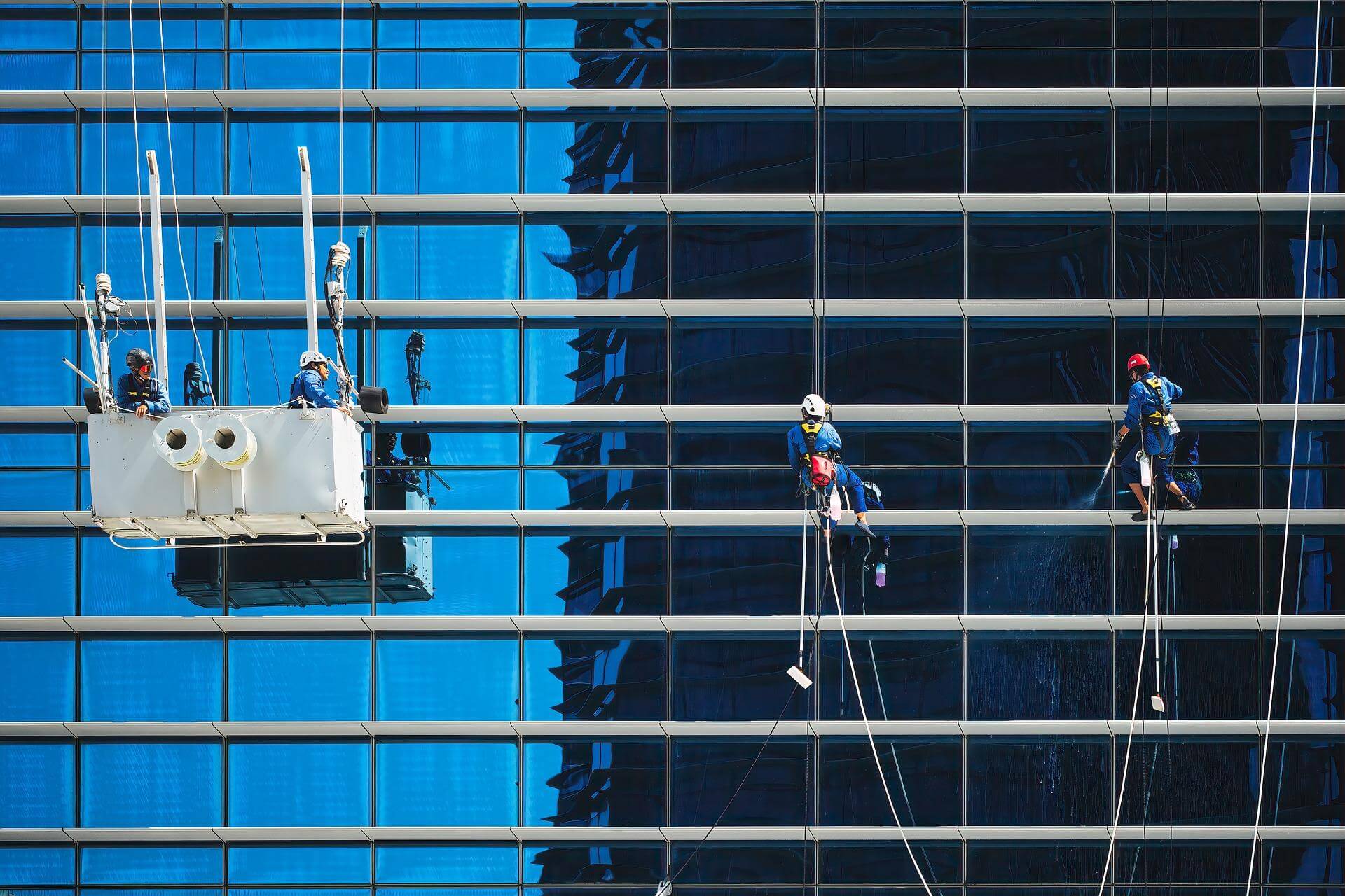 Glazenwassers reinigen de glasgevel van een hoogbouwpand